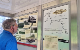 Image of man reading railway history panel at Denby Dale Station
